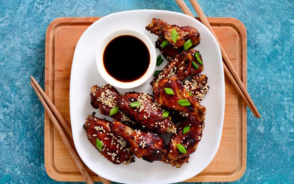 asijské jídlo servírované na talíři s omáčkou a hůlkami